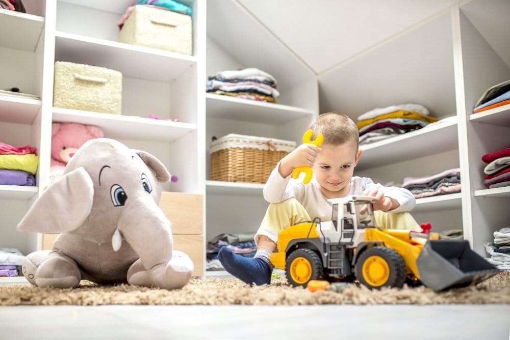 adorable little boy playing with toys while sitting floor his playroom